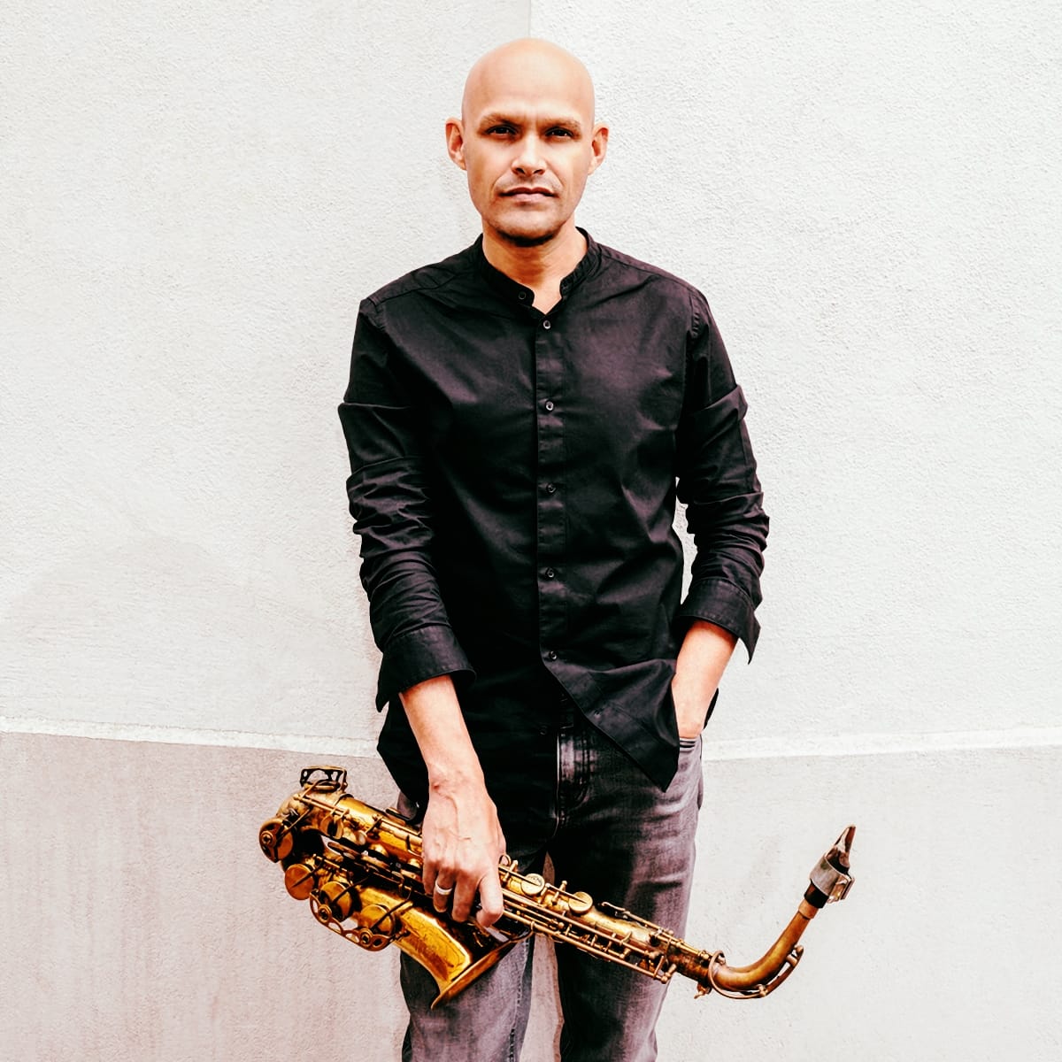 Miguel Zenon holding a saxophone, white background. Photo by Sylvain Gripoix.