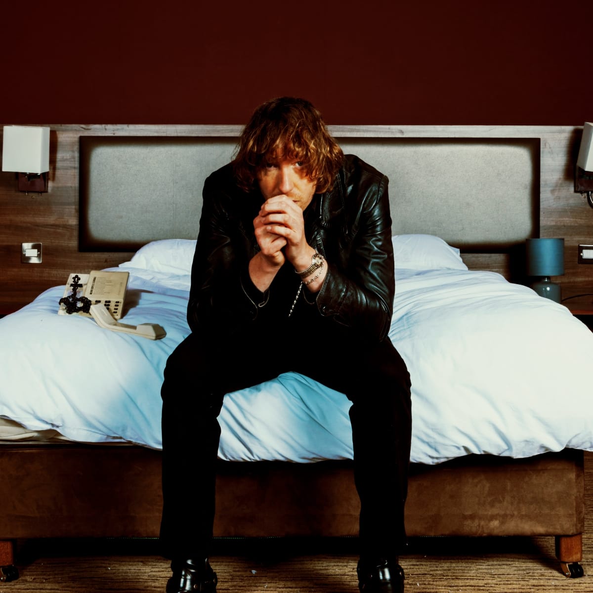 Daniel Avery seated on a hotel bed. Photo by Kalpesh Lathigra.