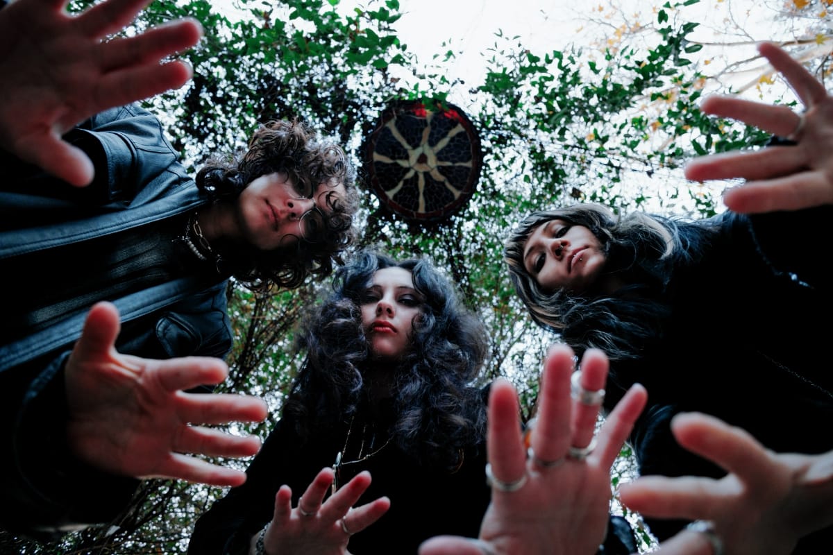 The three members of Faetooth with their hands extended toward the camera - Photo by Jon Del Real 