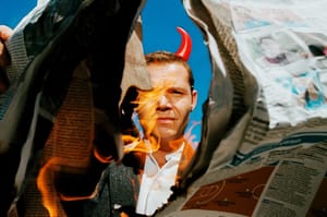 Westerman wearing devil horns and light a newspaper on fire. Photo by Eric Scaggiante.