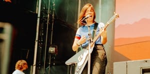 Julia Steiner of Ratboys performs with white electric guitar, singing passionately on stage with warm orange lighting.Photo by Miles Kalchik.