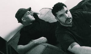 Max Scholl and Dhanya Langer of musical duo Modha photographed from below in black and white. Scholl wears facial hair, Langer wears a cap.