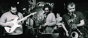 Juanma Trujillo on guitar with band in black and white jazz club performance, saxophone and other musicians visible. Photo by Joan Cortès.